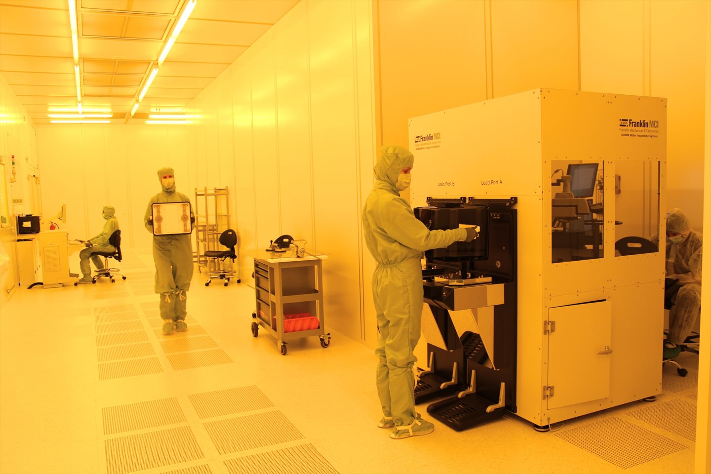Kỹ sư vi mạch trong phòng sạch cleanroom kiểm tra và vận hành máy nạp tấm wafer silicon 300mm chế tạo vi mạch